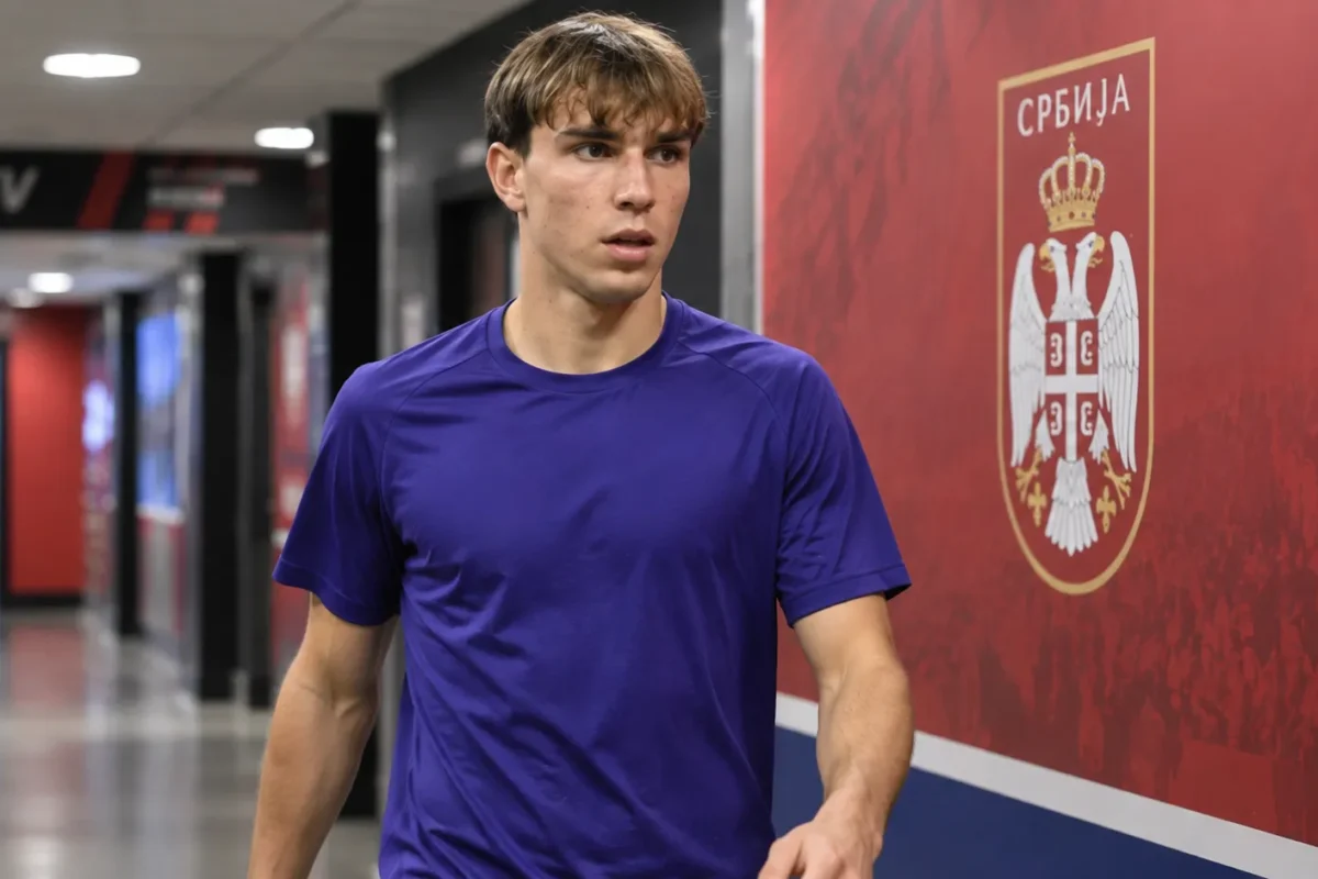 Mihajlo Cvetković in neutrale sportkleding naast een Servisch voetbalembleem in de mixed zone.