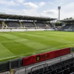 Leeg voetbalstadion met een Red Flames-spandoek langs het veld.
