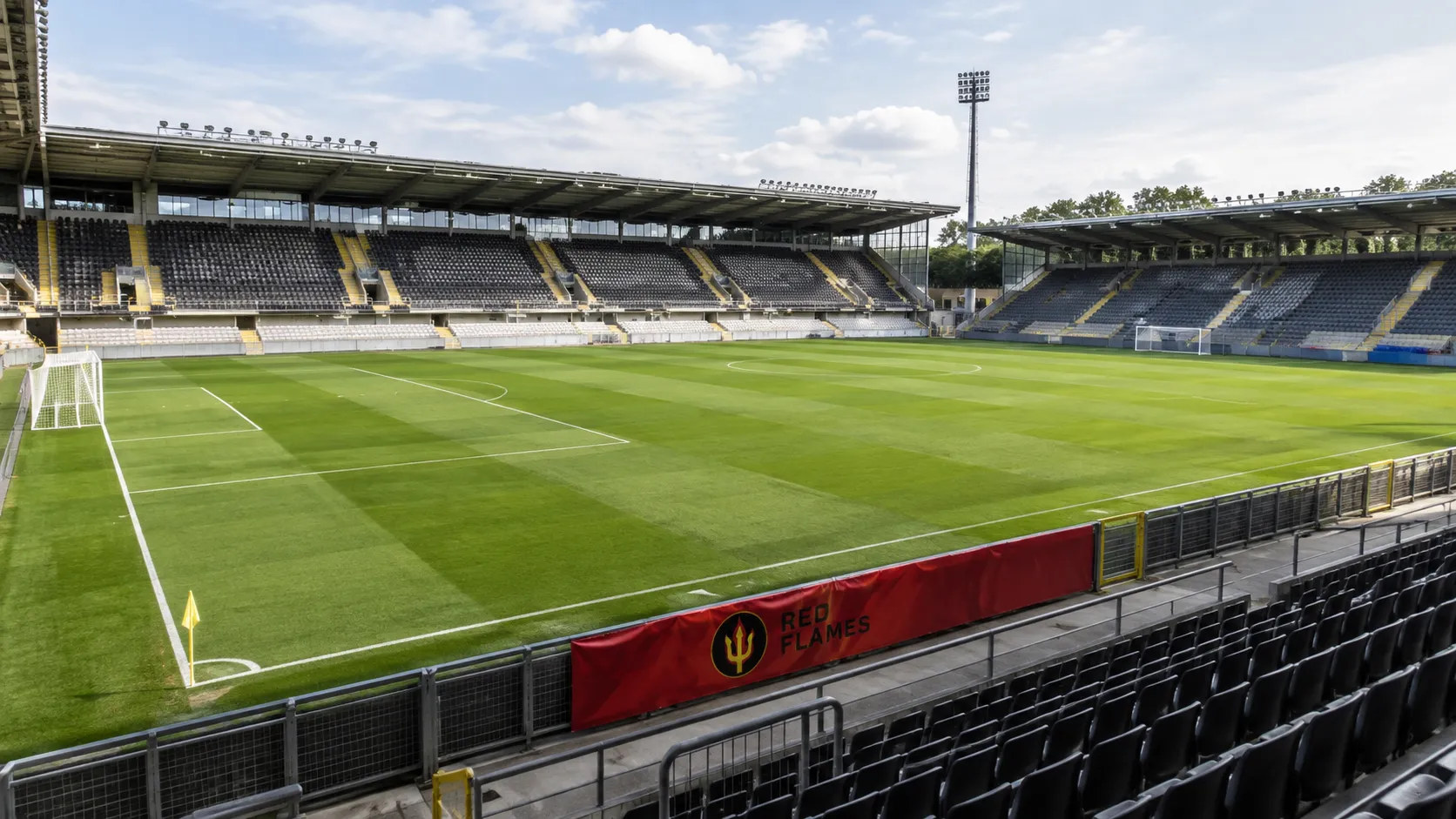 Leeg voetbalstadion met een Red Flames-spandoek langs het veld.