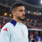 Joselu in een lichtblauw trainingsshirt van Spanje aan de rand van het veld.