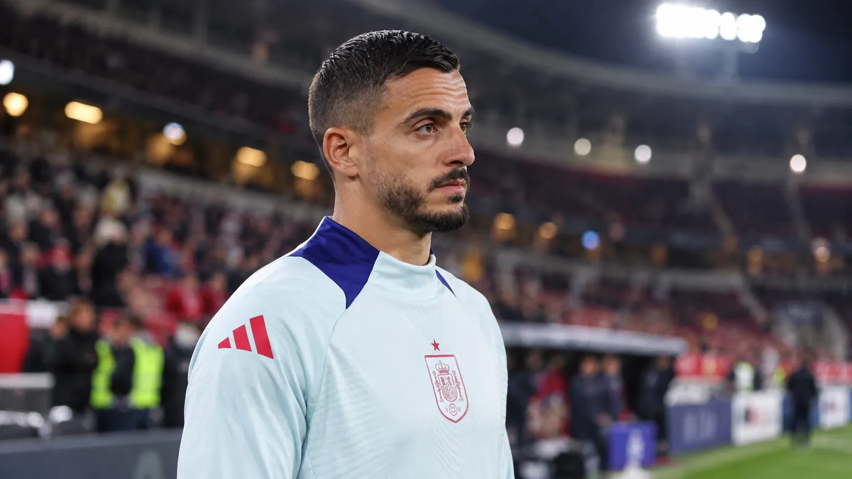 Joselu in een lichtblauw trainingsshirt van Spanje aan de rand van het veld.