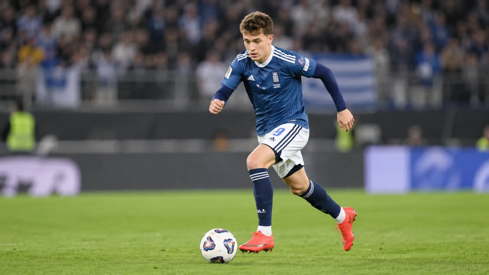 Een jonge voetballer in een blauw tenue tijdens een wedstrijd op een grasveld.
