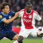 Jorthy Mokio in actie in het rood-witte shirt van Ajax tijdens een voetbalwedstrijd.