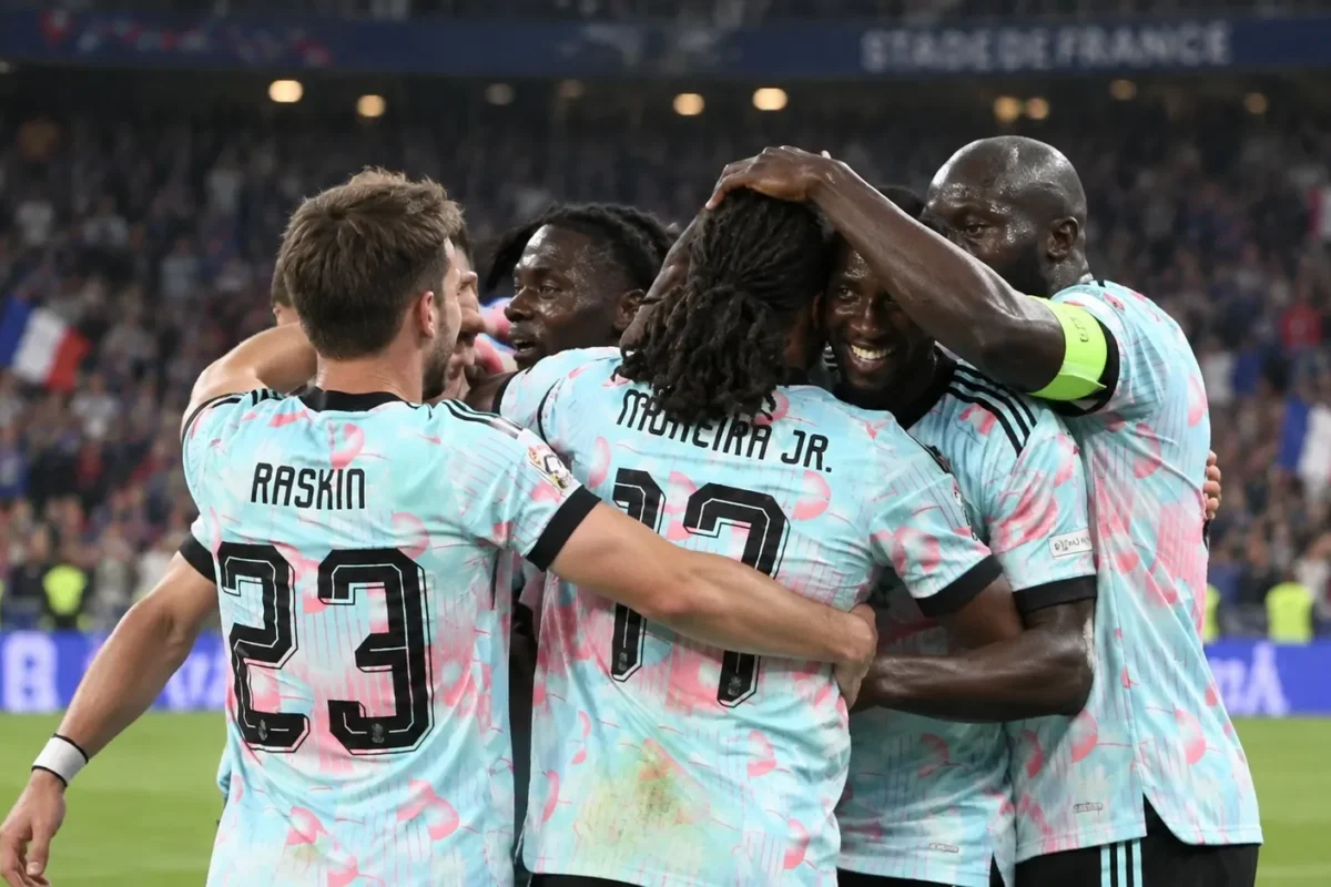 Een groep Belgische spelers viert op het veld in lichtblauwe shirts.