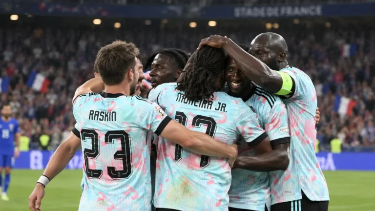 Een groep Belgische spelers viert op het veld in lichtblauwe shirts.