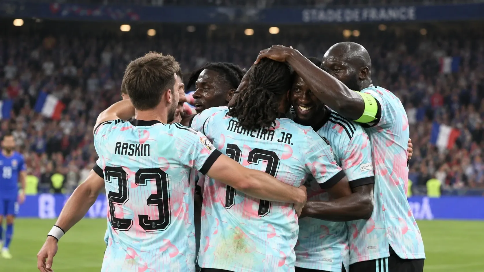 Een groep Belgische spelers viert op het veld in lichtblauwe shirts.