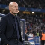 Een Franse coach in donker pak naast de dug-out na een interland.