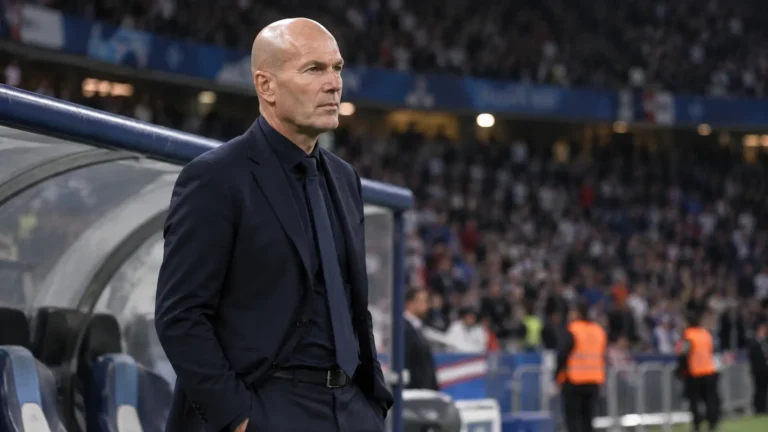 Een Franse coach in donker pak naast de dug-out na een interland.