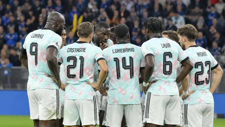 Belgische internationals in lichte wedstrijdshirts die zich op het veld groeperen.