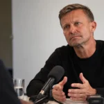 Jesse Marsch tijdens een interview aan een tafel in een rustige binnenruimte.