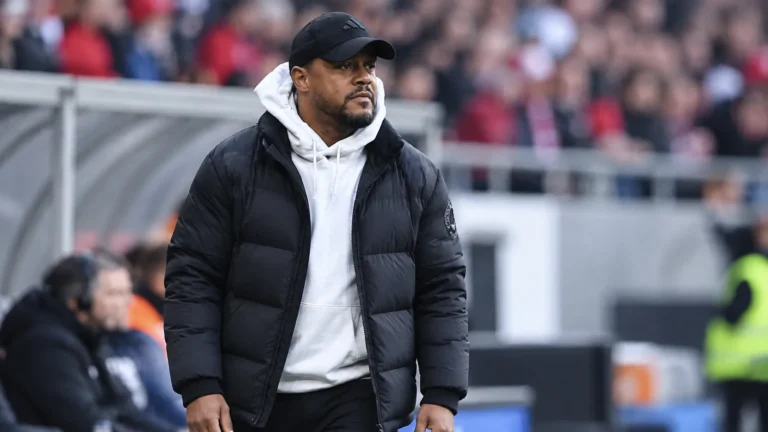 Een coach uit de technische staf langs de zijlijn van een voetbalstadion.