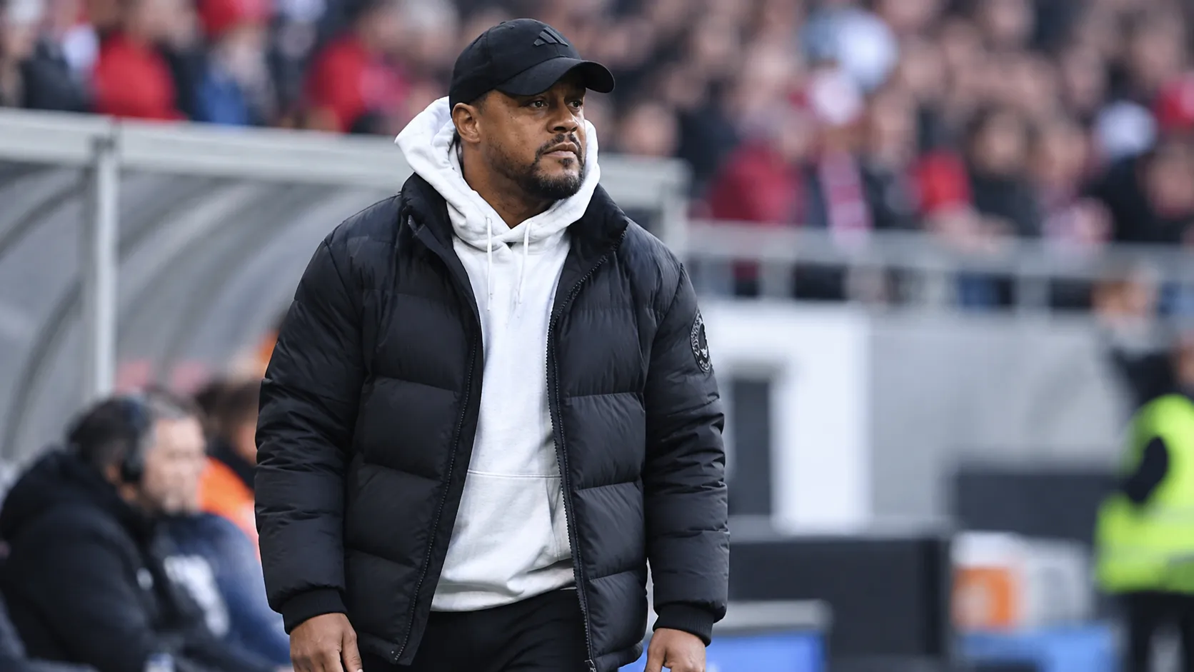 Een coach uit de technische staf langs de zijlijn van een voetbalstadion.