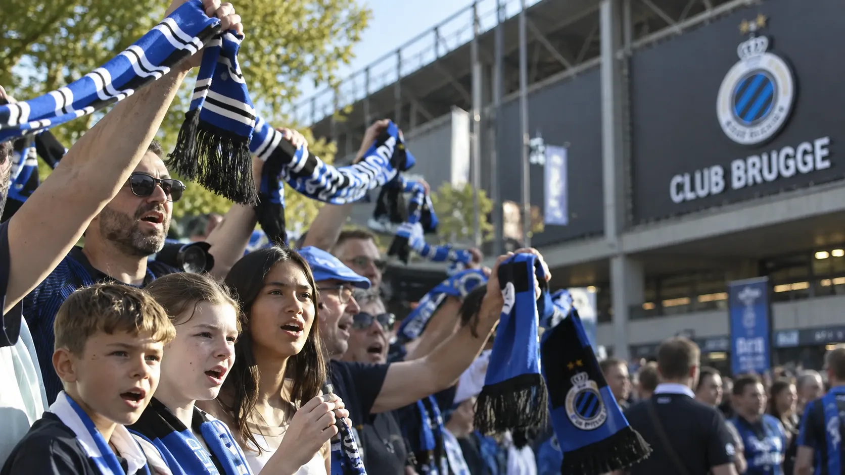 Een groep Club Brugge-supporters zwaait met blauw-zwarte sjaals buiten het stadion.
