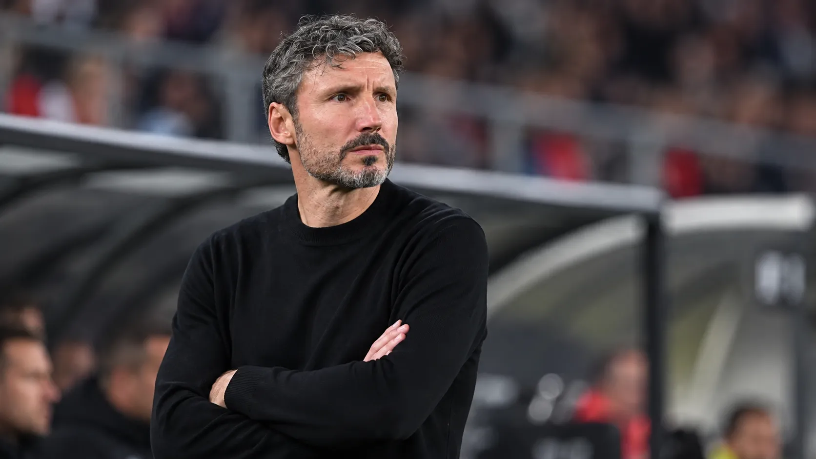 Mark van Bommel kijkt geconcentreerd vanuit de technische zone van een interlandstadion.