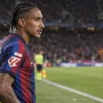 Raphinha in het shirt van FC Barcelona langs de zijlijn van een voetbalveld.