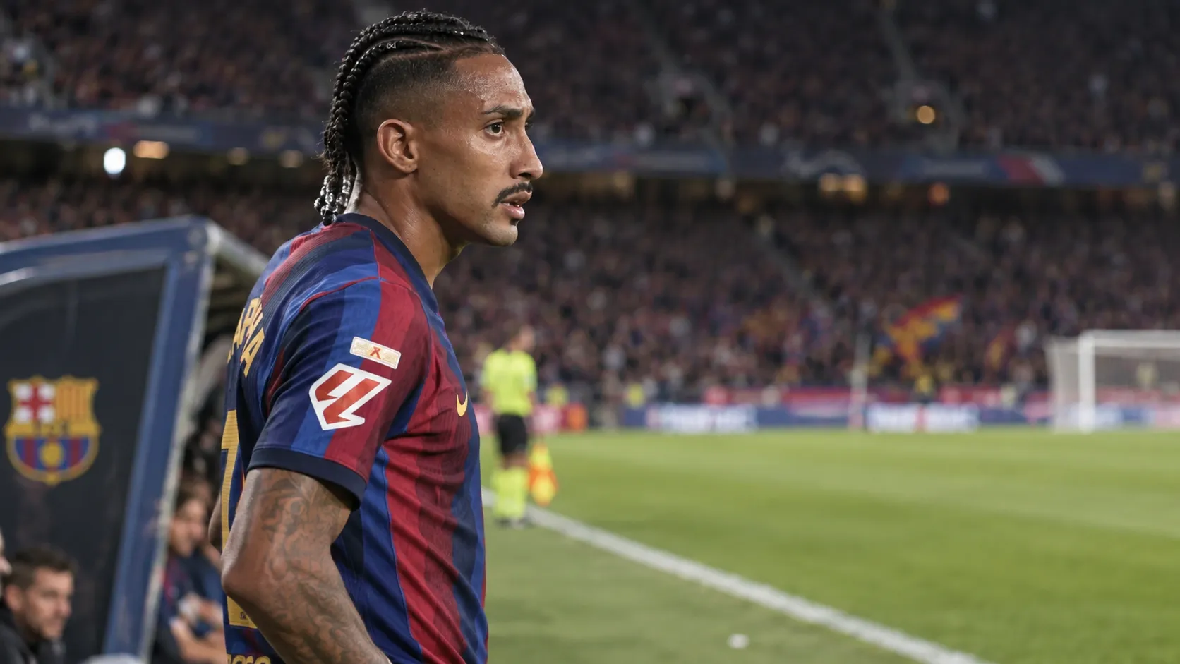 Raphinha in het shirt van FC Barcelona langs de zijlijn van een voetbalveld.