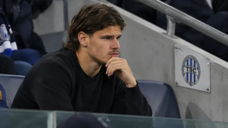 Milos Kerkez in neutrale kleding op de tribune bij een wedstrijd van FK TSC.