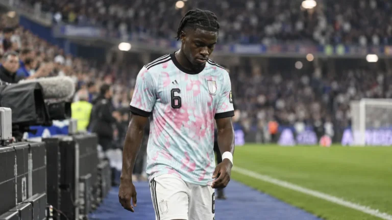Romeo Lavia wandelt in een wit wedstrijdtenue op het veld na een interland.