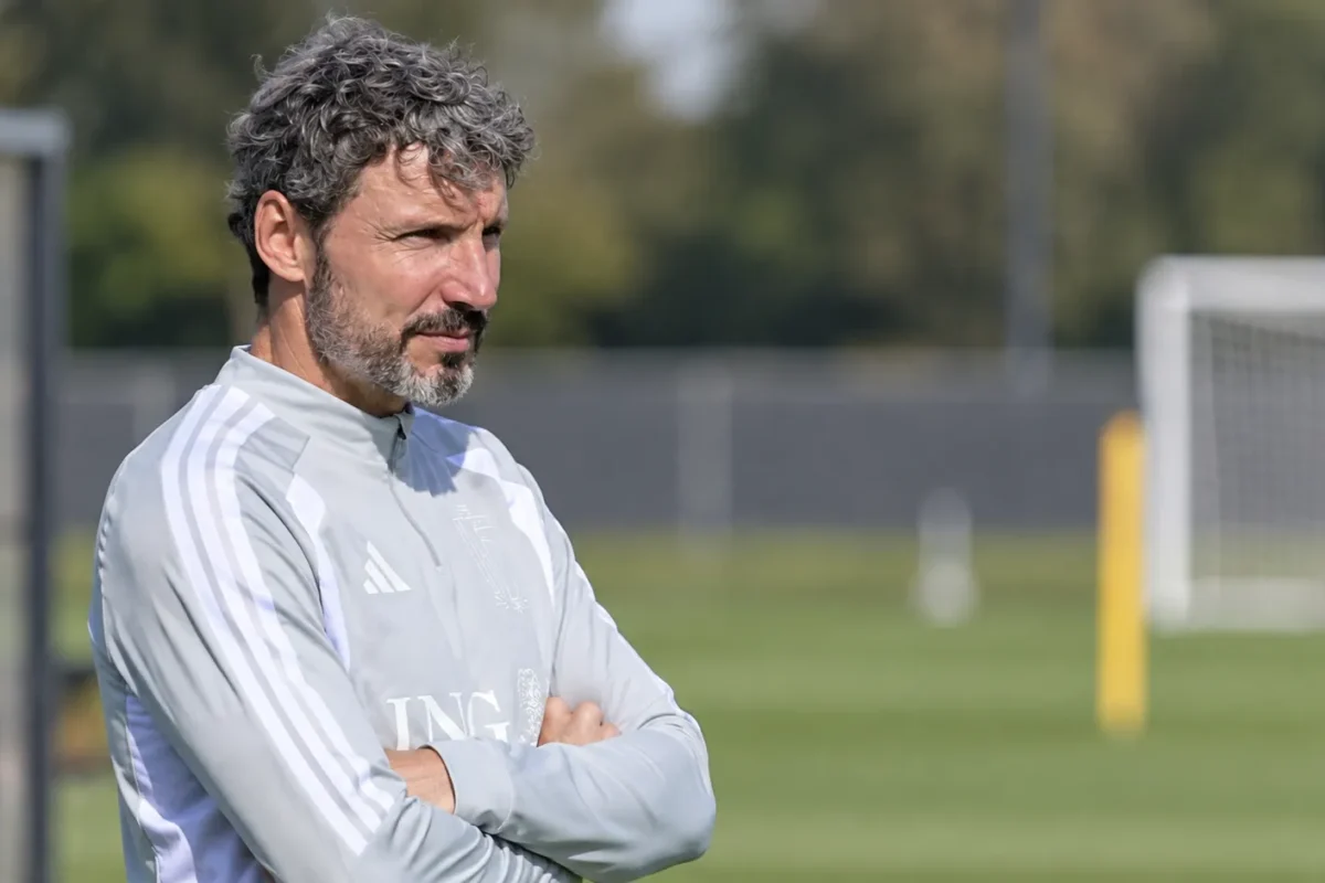 Mark van Bommel langs een trainingsveld in een lichtgrijze trainingstop.