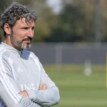 Mark van Bommel langs een trainingsveld in een lichtgrijze trainingstop.