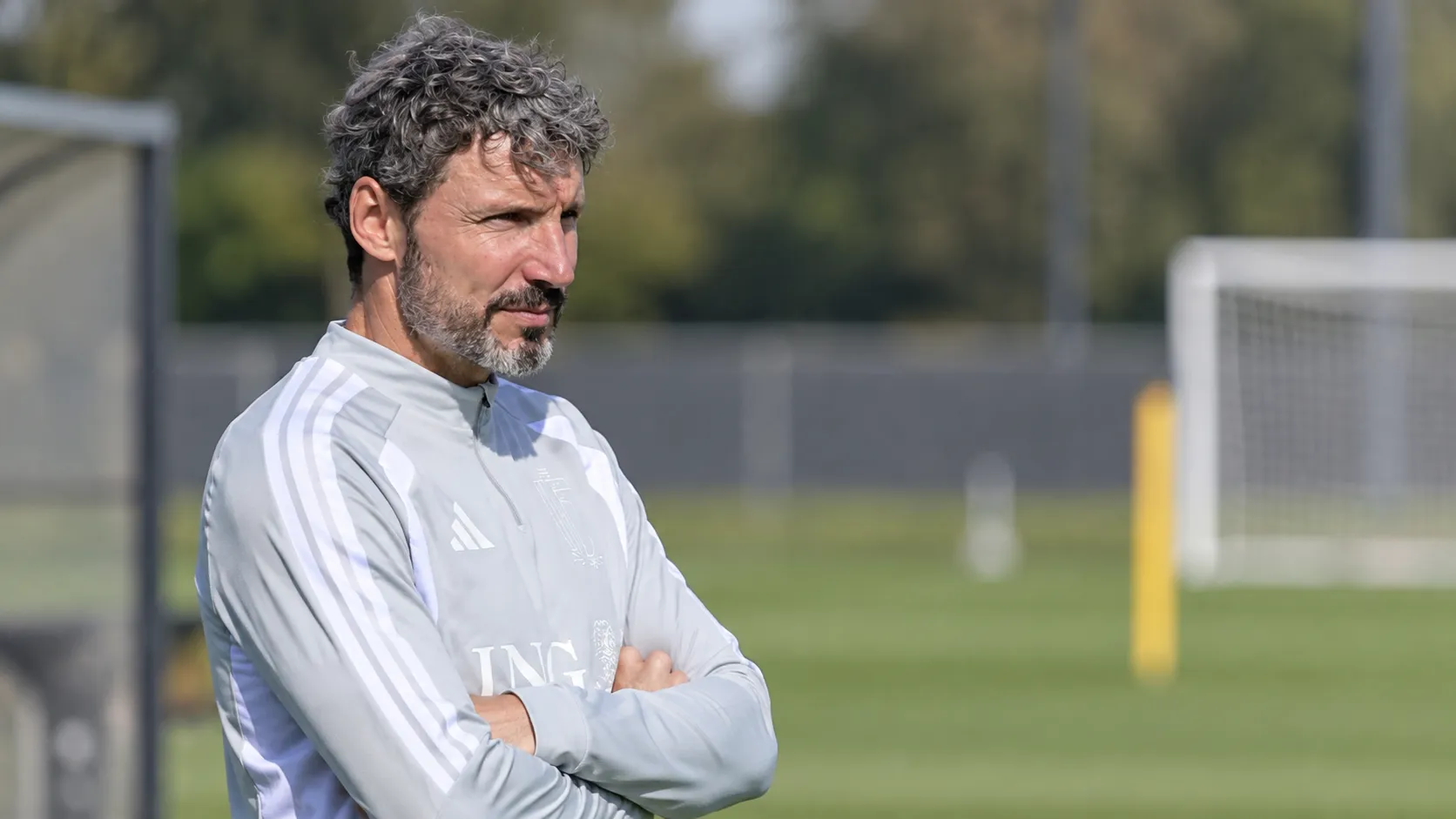 Mark van Bommel langs een trainingsveld in een lichtgrijze trainingstop.