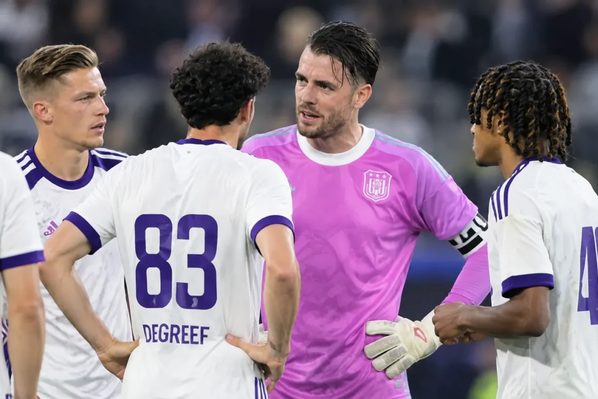 Een groep spelers van RSC Anderlecht verzamelt zich na een wedstrijd op het veld.