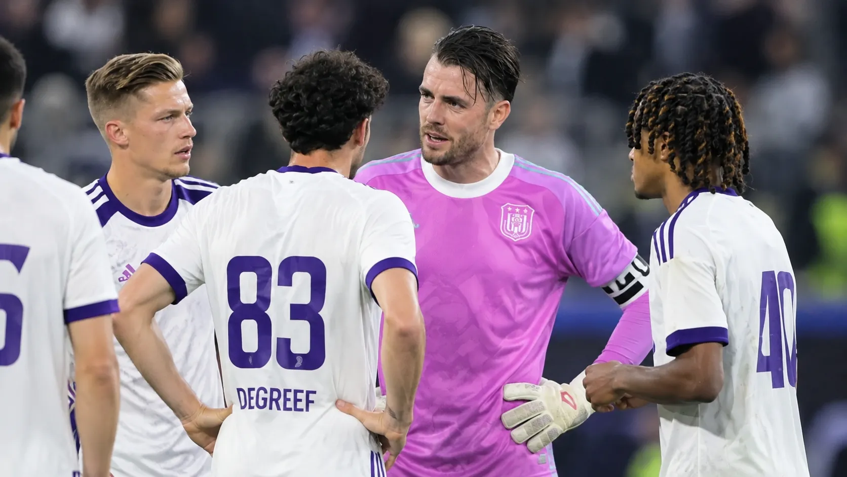 Een groep spelers van RSC Anderlecht verzamelt zich na een wedstrijd op het veld.
