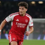 Christos Tzolis in Arsenal-tenue op het veld tijdens een avondwedstrijd.