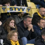 Een groep STVV-supporters in de tribune met een blauw-geel-witte sjaal.