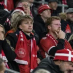 Deense supporters in een stadiontribune met een sjaal van de nationale ploeg.