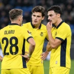 Drie spelers van Union overleggen op het veld in gele wedstrijdtenues.