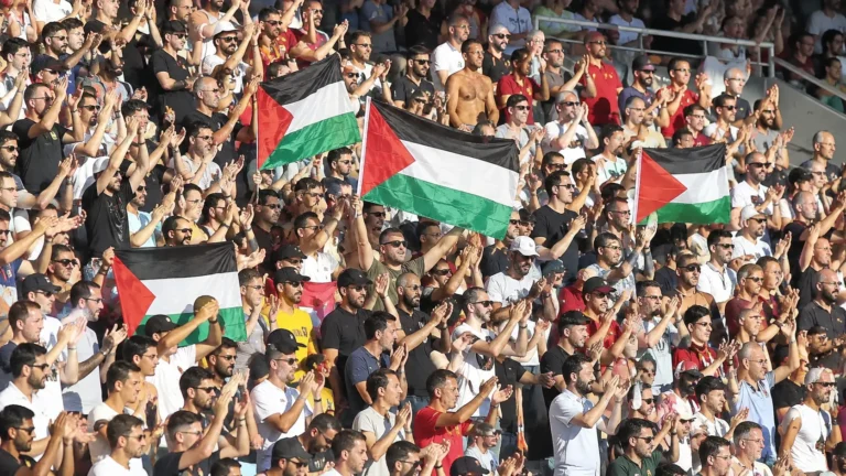 Supporters op de tribunes houden Palestijnse vlaggen omhoog tijdens een solidariteitsactie.