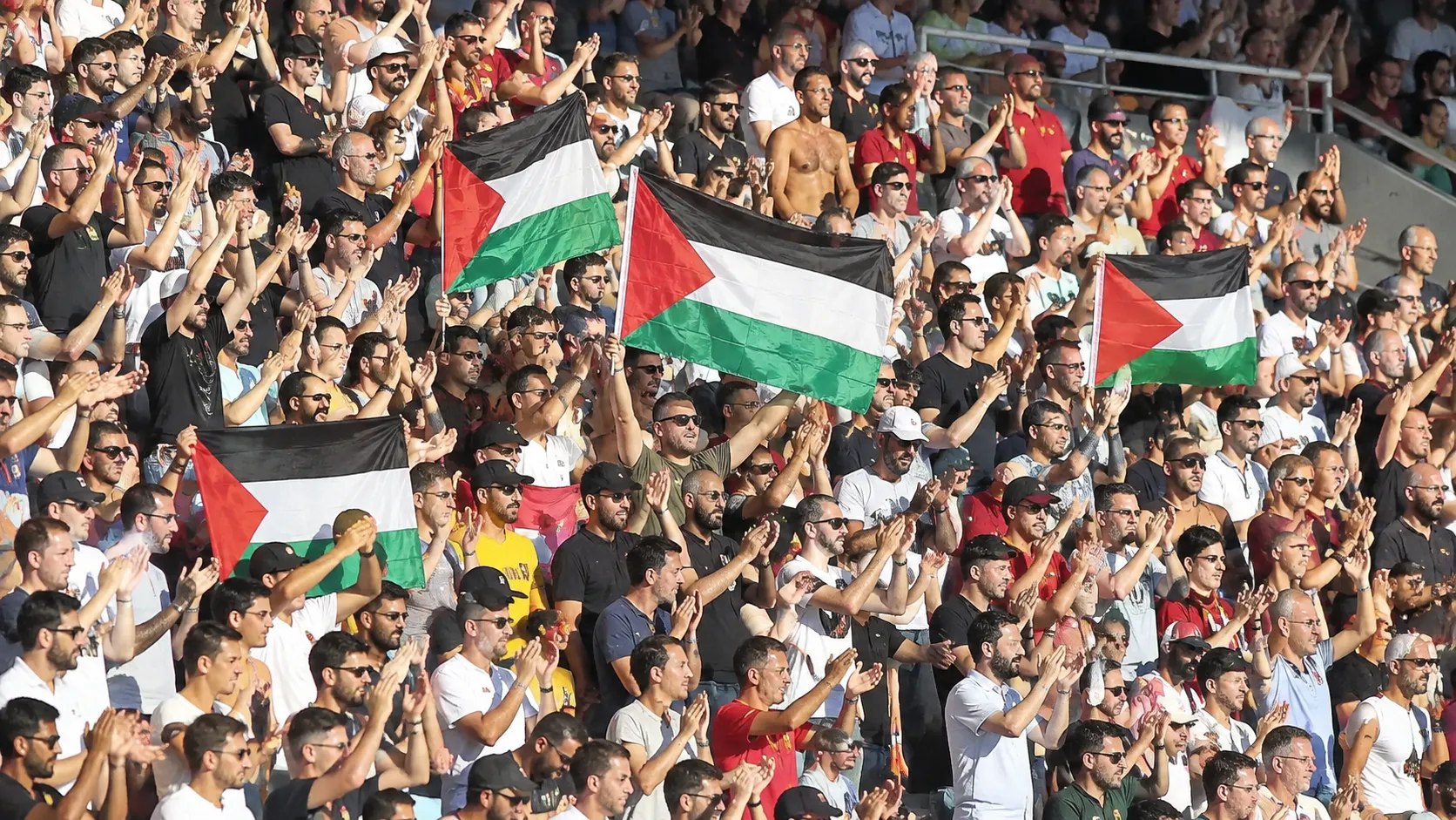 Supporters op de tribunes houden Palestijnse vlaggen omhoog tijdens een solidariteitsactie.