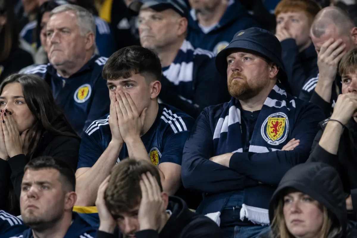 Teleurgestelde Schotse supporters op de thuistribune met een sjaal van Schotland.