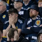 Teleurgestelde Schotse supporters op de thuistribune met een sjaal van Schotland.