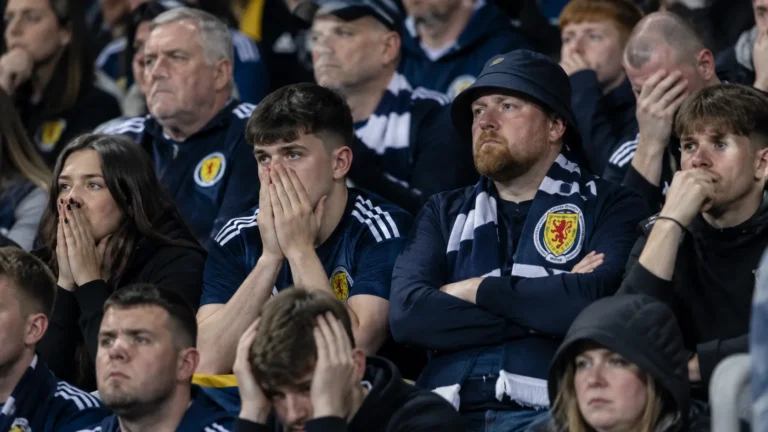 Teleurgestelde Schotse supporters op de thuistribune met een sjaal van Schotland.
