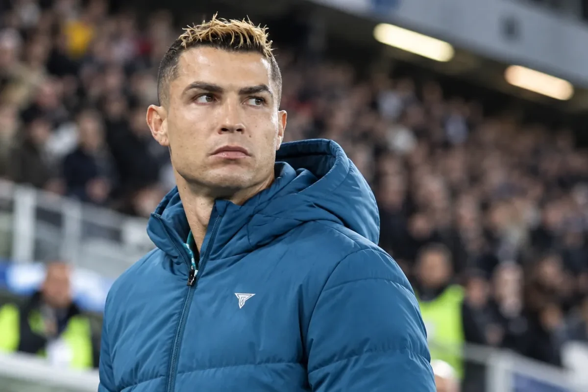 Cristiano Ronaldo in een blauwe Portugal-jas aan de rand van een stadion.