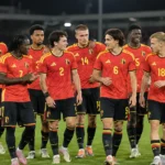 Belgische U21-spelers in rode tenues verzamelen op het veld na een wedstrijd.