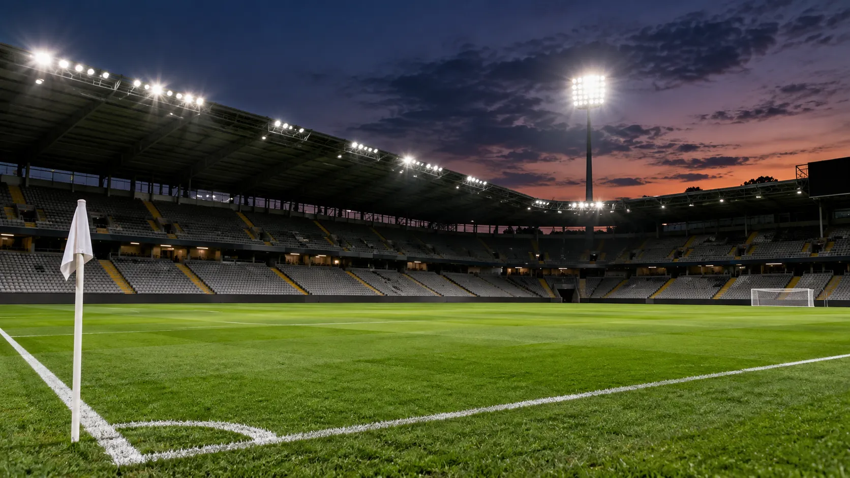 Een leeg voetbalveld onder stadionlichten bij valavond.