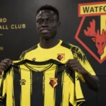 Krépin Diatta poseert tijdens zijn officiële voorstelling bij Watford in clubtenue.