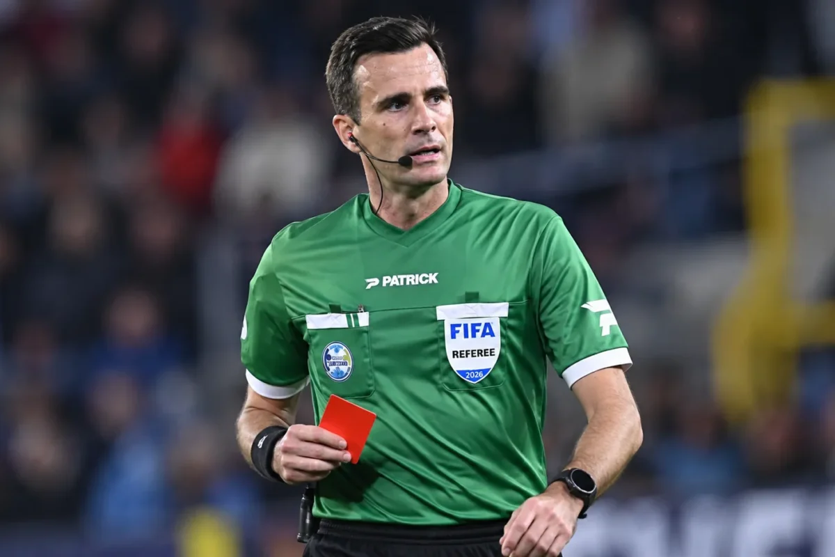 Erik Lambrechts als scheidsrechter met een rode kaart tijdens een voetbalwedstrijd.