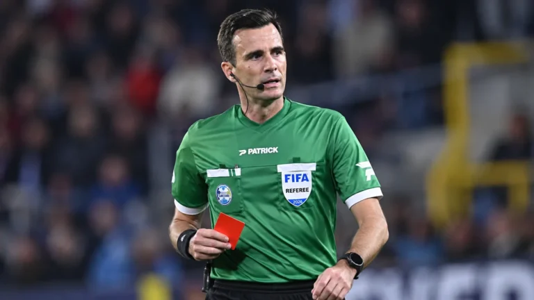 Erik Lambrechts als scheidsrechter met een rode kaart tijdens een voetbalwedstrijd.