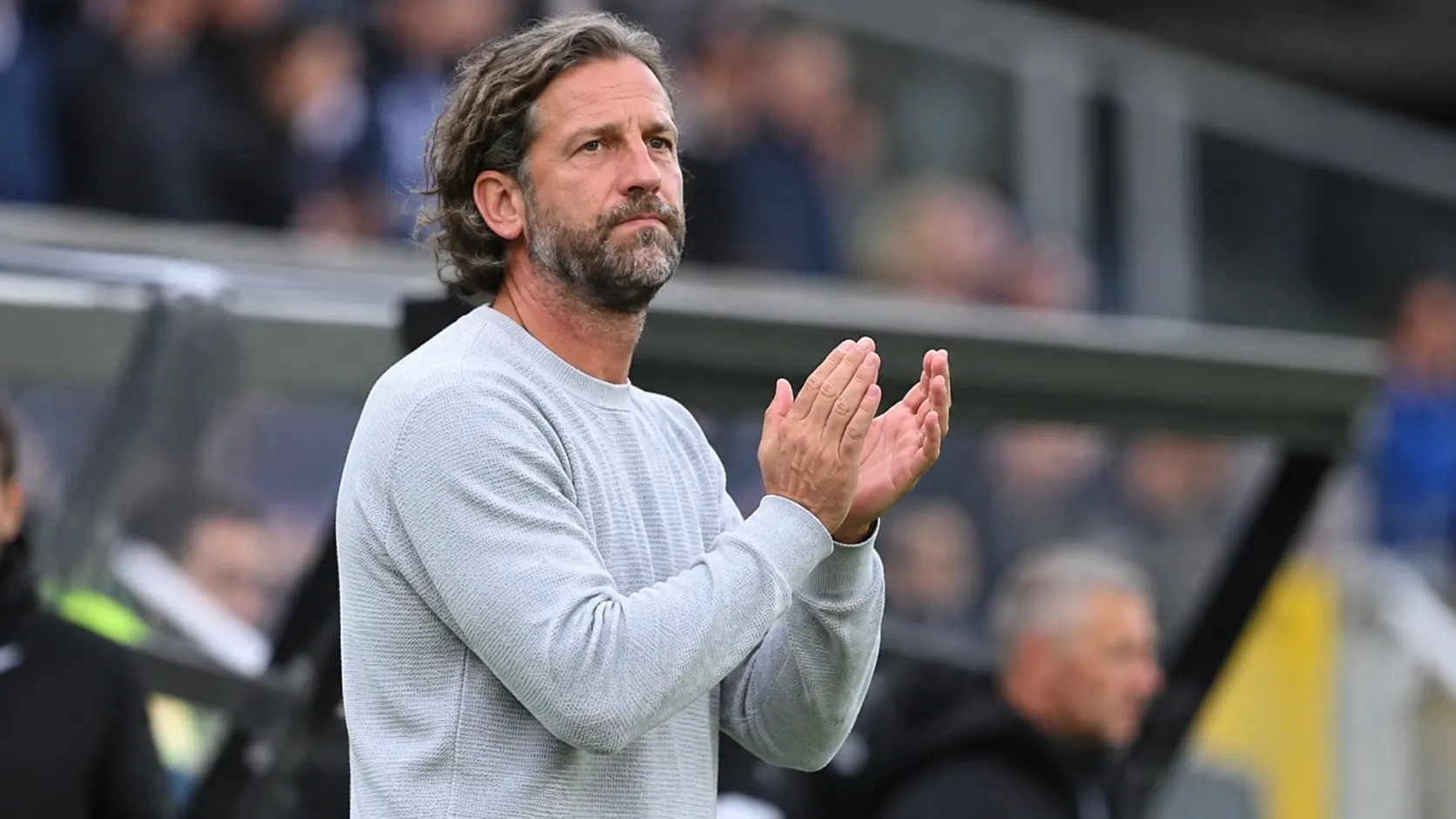 Rik De Mil applaudisseert langs de zijlijn in een stadion.