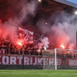 Rood-witte supporters van KV Kortrijk zorgen met rookfakkels voor sfeer achter het doel.