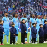 Spelers van Congo staan opgesteld voor een interland met jeugdmascottes voor hen.