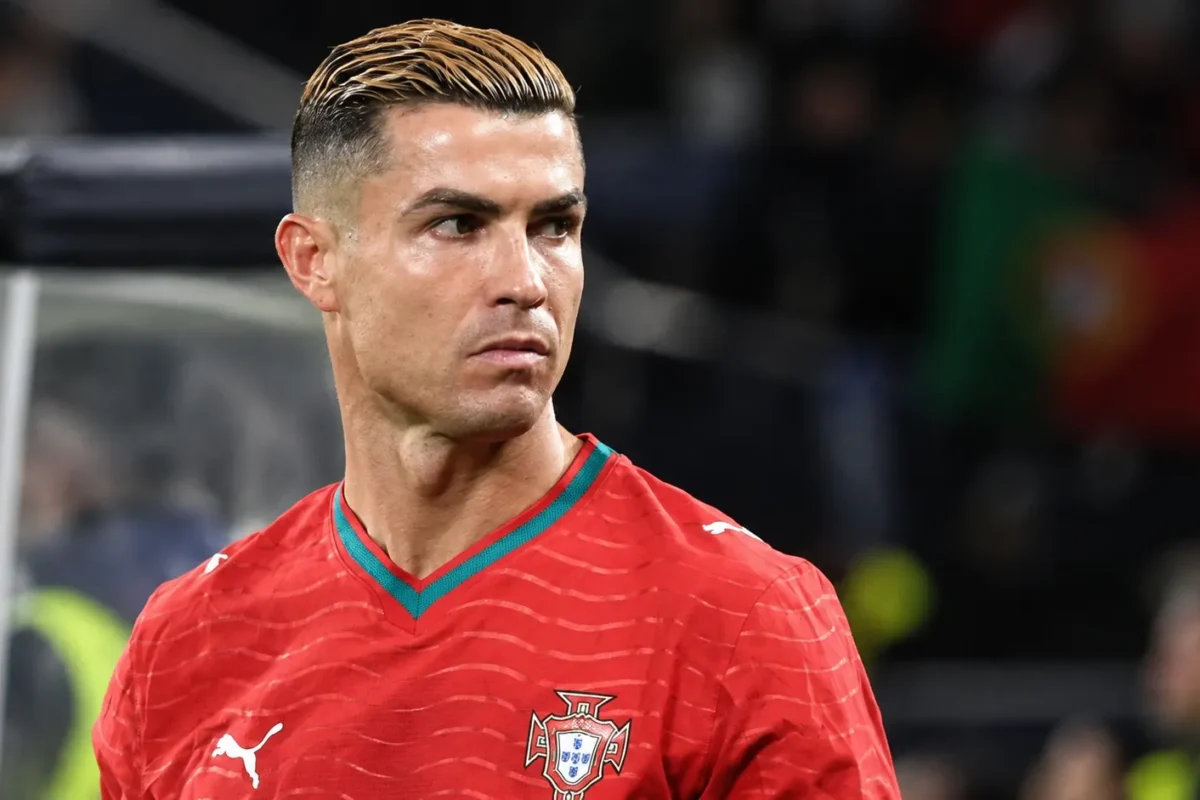 Een speler van Portugal in een rood shirt kijkt opzij in een stadion.