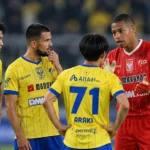 Voetballers in gele tenues en een doelman in rood verzamelen zich op het veld.