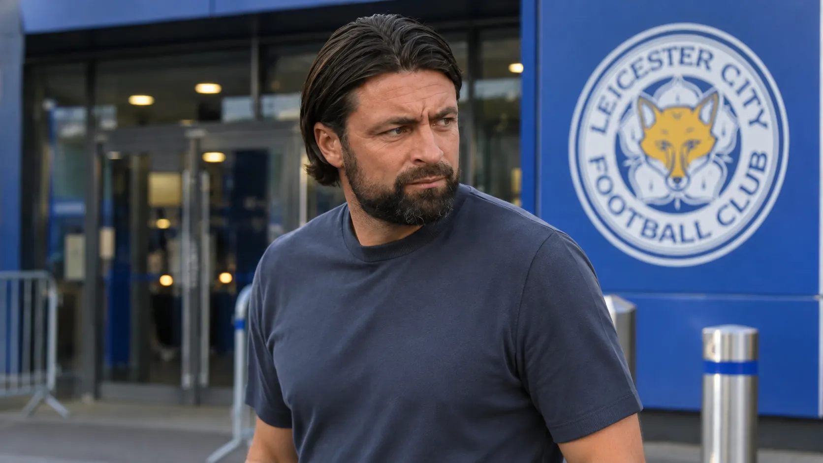 Russell Martin bij een stadioningang met een Leicester City-embleem op een vast bord achter hem.