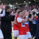 Een groep spelers en stafleden van KV Kortrijk applaudisseert richting de tribunes.