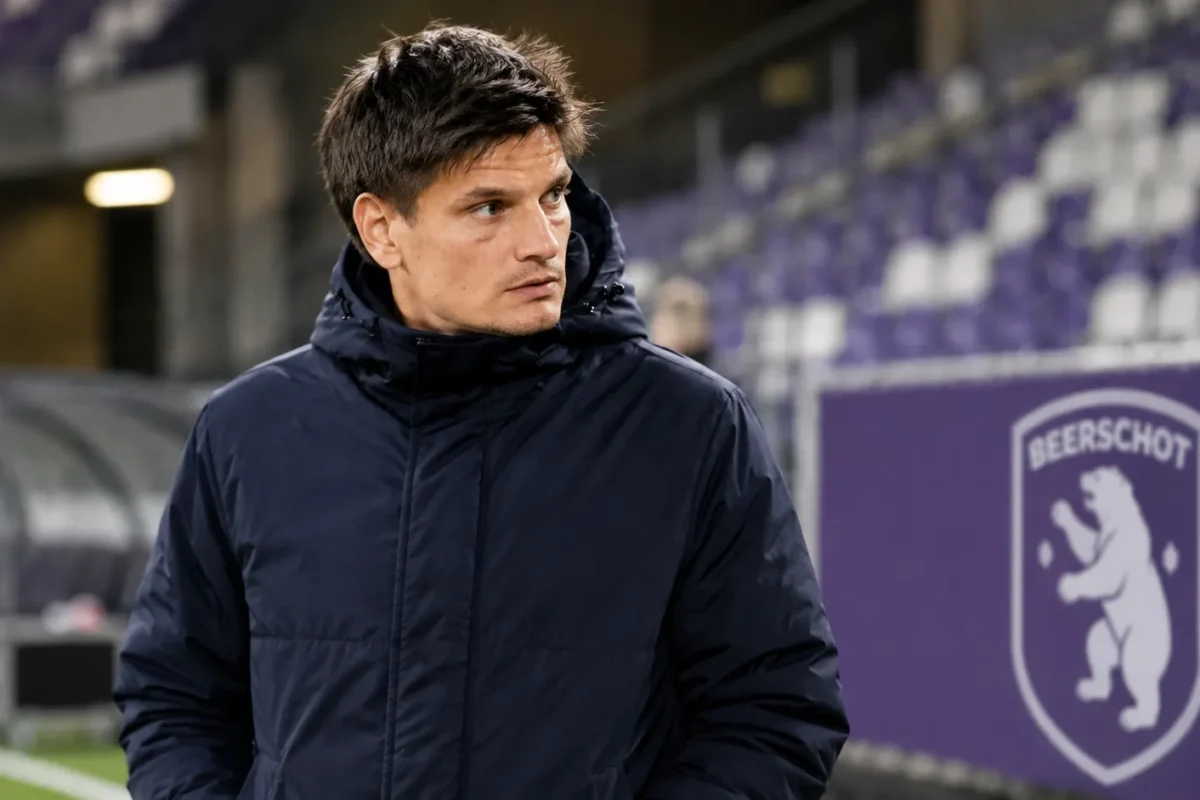 Jelle Vossen in een donkere jas langs de zijlijn van een Beerschot-stadion.